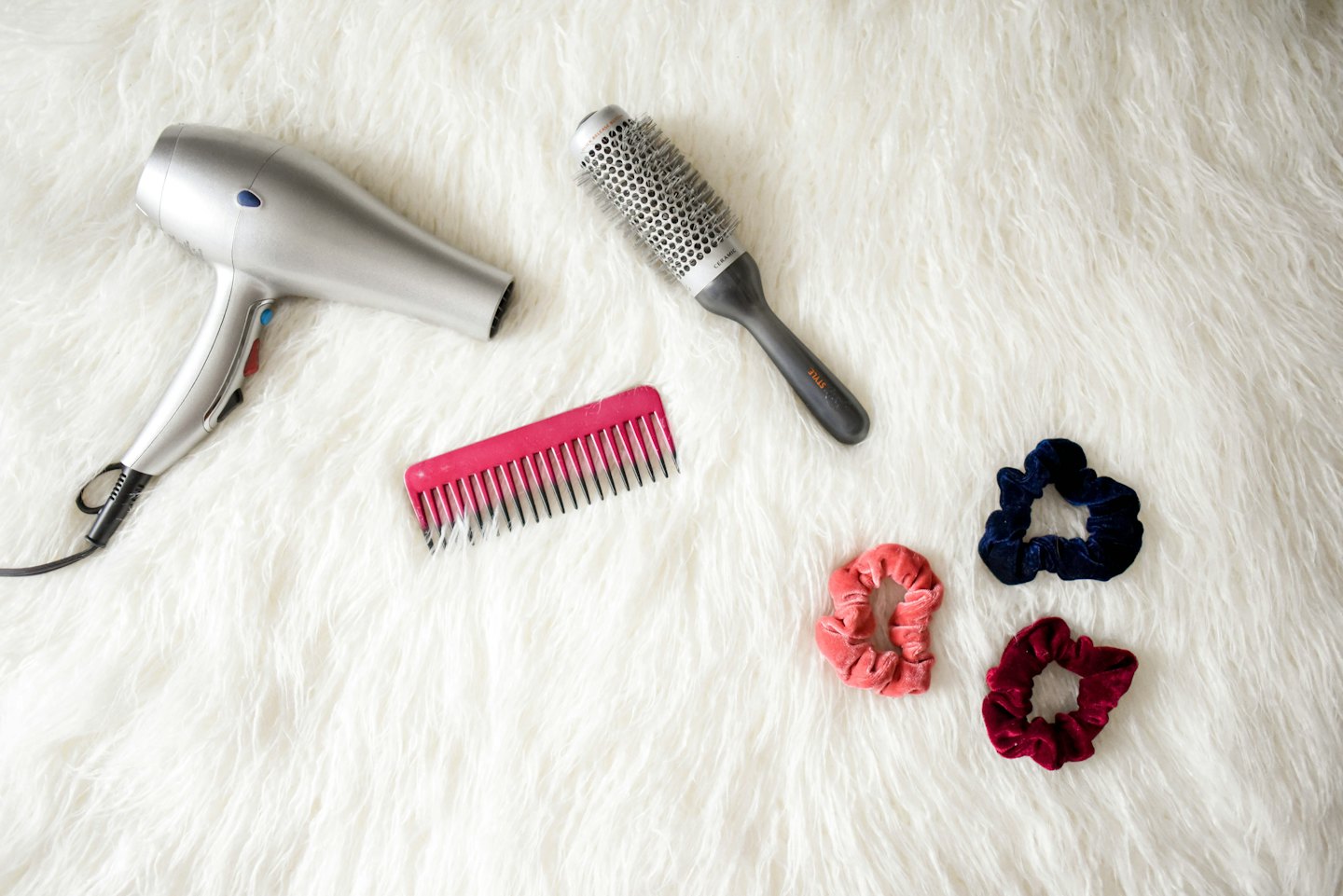 Hair care tools and accessories arranged on a white rug.